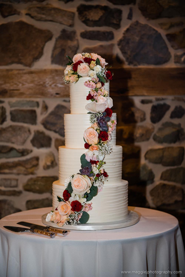 4 Tier rustic textured buttercream wedding cake decorated with cascading fresh flowers