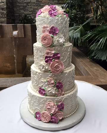 4 Tier buttercream wedding cake, decorated with buttercream scrolls, buttercream borders, cascading hot pink, blush and white buttercream flowers delivered at the Eden Resort in Lancaster PA