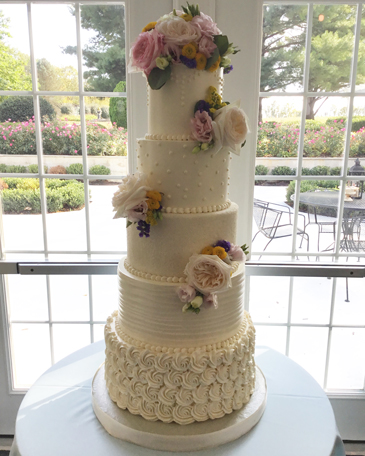 5 Tier buttercream wedding cake, decorated with buttercream pearl swags, buttercream Swiss dots, rosettes, buttercream pearl borders and fresh flowers