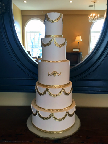 5 Tier regal buttercream wedding cake, decorated with gold floral fondant swags, a gold fondant emblem and gold fondant borders delivered at Linwood Estate in Carlisle PA