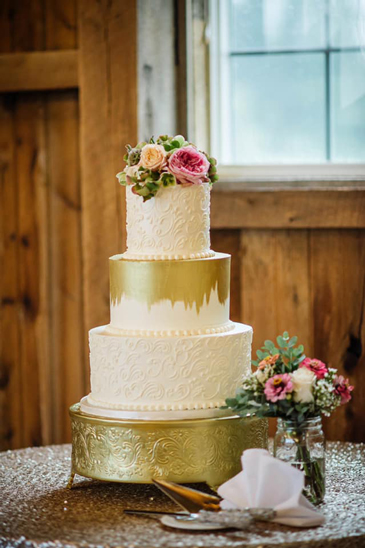 3 Tier buttercream wedding cake, decorated with buttercream scrolls, edible gold paint and fresh flowers delivered at Wyndridge Farm Dallastown PA
