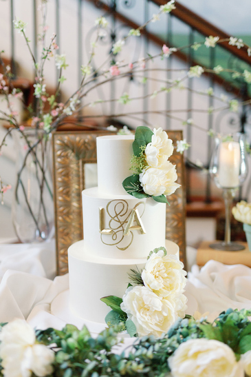 3 Tier simply clean buttercream wedding cake, decorated with gold ampersand (the and sign) and initials, white flowers and greenery, delivered at Box Hill Mansion in York PA
