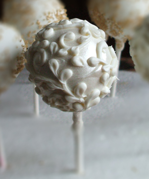 Chocolate raspberry cake pop dipped in white chocolate and decorated with white chocolate scrolls