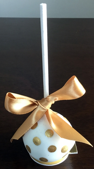 Chocolate cake pops dipped in white chocolate decorated with edible gold dots and gold ribbons