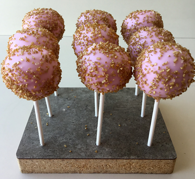 Cake pops dipped in pink chocolate decorated with gold sugar crystals