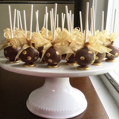 Cake pops dipped in milk chocolate and decorated with gold dots and gold ribbons