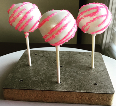 Cake pops dipped in white chocolate, decorated with white chocolate stripes and pink sugar crystals