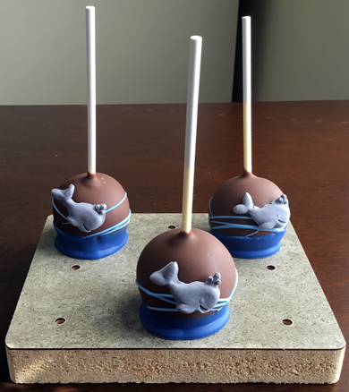 Nautical themed cake pops. Yellow cake pops, dipped in dark chocolate decorated with light and dark chocolate and grey fondant whales
