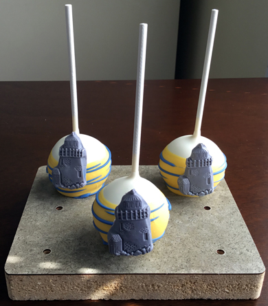 Nautical themed cake pops. Chocolate cake pops, dipped in white chocolate and yellow chocolate, decorated with blue stripes and silver fondant light houses