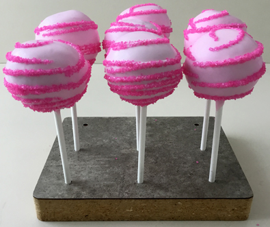 Cake pops dipped in light pink chocolate with hot pink sugar crystal stripes