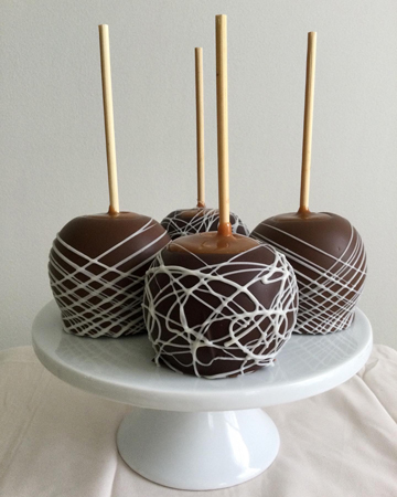 Caramel apples, dipped in milk and dark chocolate and decorated with white chocolate stripes and swirls