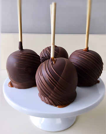 Caramel apples, dipped in milk and dark chocolate and decorated with  milk chocolate stripes