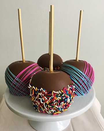 Milk chocolate caramel apples, decorated with confetti and pink and blue chocolate stripes