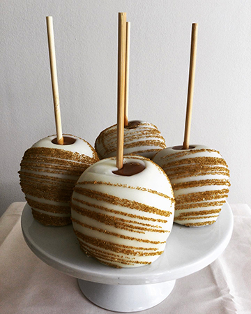 Caramel apples, dipped in white chocolate and decorated with gold sanding sugar stripes