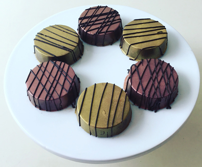 Oreo cookies, dipped in dark chocolate, painted with edible metallic colors and decorated with dark chocolate stripes