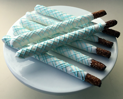 Tall pretzels dipped in white chocolate with light blue chocolate stripes