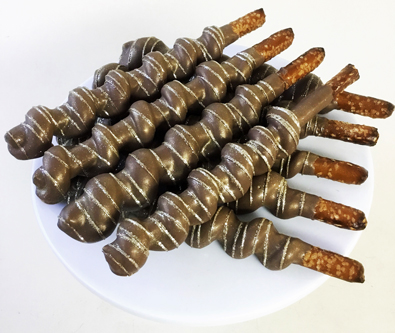 Tall pretzels wrapped with caramel and dipped in milk chocolate with edible gold glitter stripes