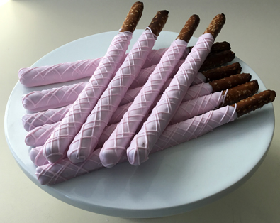 Tall pretzels dipped in light pink chocolate with light pink chocolate stripes