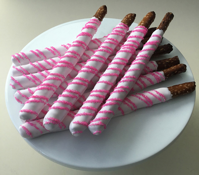 Tall pretzels dipped in light pink chocolate with hot pink sugar crystal stripes