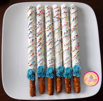 Tall pretzels rods dipped in white chocolate, decorated with white chocolate stripes, colored non perils and sugar flowers