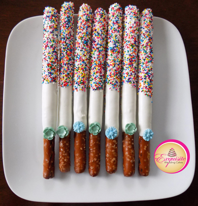 Tall pretzels rods dipped in white chocolate, decorated with colored non perils and sugar flowers