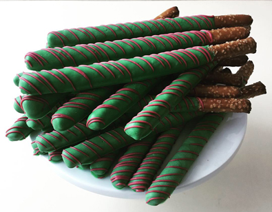 Tall pretzel sticks dipped in dark green chocolate with burgundy chocolate stripes
