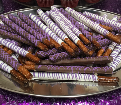 Tall pretzel sticks dipped in white and milk chocolate with purple chocolate stripes