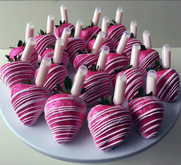 Strawberries dipped in light pink chocolate, covered in edible hot pink glitter, decorated with light pink chocolate stripes and strawberies and cream liqueur infusion tubes