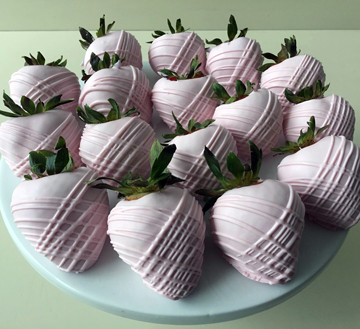 Strawberries dipped in light pink chocolate, decorated with criss cross chocolate stripes