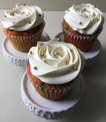 Confetti cupcakes, topped with buttercream rosettes and decorated with gold sugar pearls
