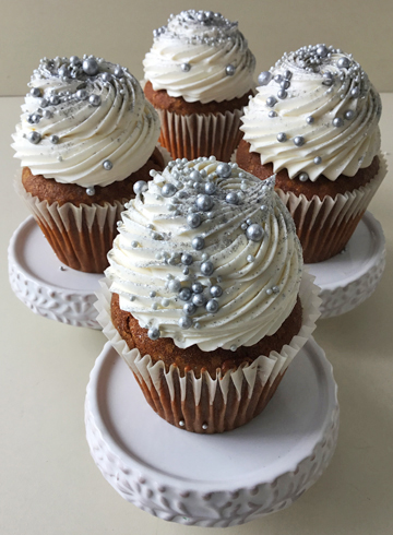 Pumpkin spice cupcakes, topped with swirls of vanilla buttercream using a French star tip and decorated with edible glitter and silver sugar pearls