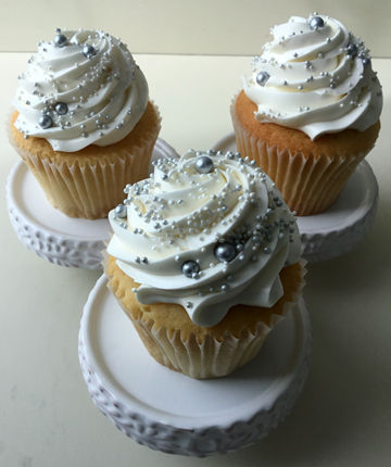 Vanilla cupcakes, topped with swirls of vanilla buttercream, using a star tip and sprinkled with white and silver nonpareils and silver sugar pearls