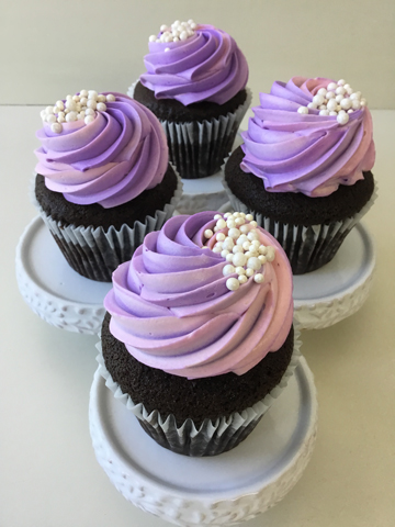 Chocolate cupcakes, topped with swirls of purple and pink vanilla buttercream and decorated with edible pearls
