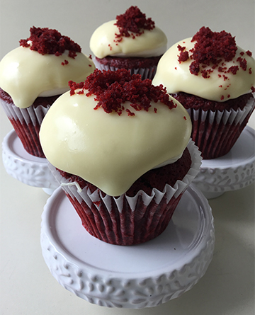 Red velvet cupcakes, topped with cream cheese icing, white chocolate ganache and red velvet cake crumbles
