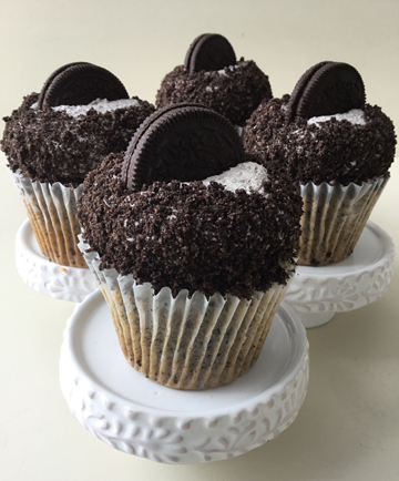 Oreo cookies and cream cupcakes, filled with ganache, topped with Oreo cookies and cream buttercream, with edges covered in crumbled Oreo cookies and topped with Oreo cookies