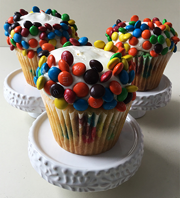 Vanilla M&M cupcakes, topped with vanilla buttercream, with edges covered in mini M&M's