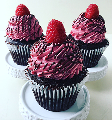 Chocolate cupcakes, filled with ganache, topped with raspberry buttercream, drizzled with ganache and topped with fresh raspberries