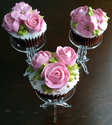 Red velvet cupcakes filled with cream cheese icing, iced with vanilla buttercream and decorated with pink buttercream roses and blossom flowers