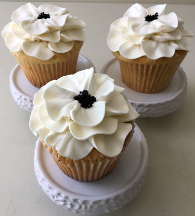 Cupcakes decorated with white fantasy buttercream flowers with black centers