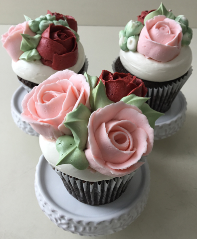 Chocolate cupcakes decorated with red and blush buttercream roses and buttercream buds
