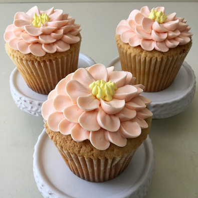 Cupcakes decorated with peach and yellow buttercream flowers