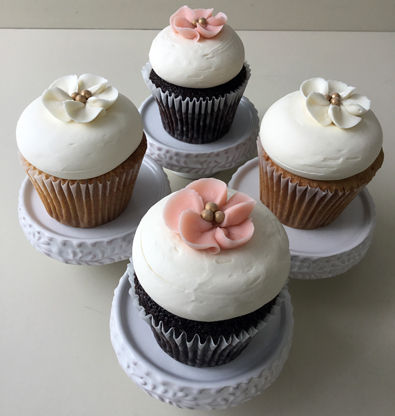 Caramel cupcakes topped with vanilla buttercream and decorated with white blossom buttercream flowers and chocolate cupcakes, topped with Bailey's buttercream and decorated with blush blossom buttercream flowers