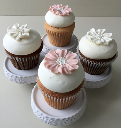 Pumpkin spice cupcakes topped with cream cheese icing and decorated with white  buttercream flowers and pink champagne cupcakes topped with vanilla buttercream and decorated with blush buttercream flowers