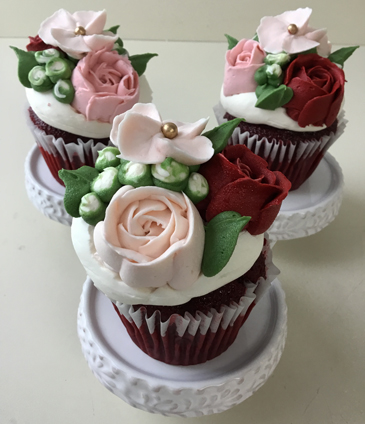 Red velvet cupcakes decorated with red and blush buttercream roses and buttercream buds