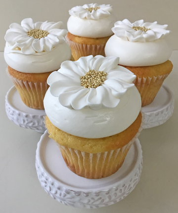 Vanilla cupcakes, filled with cream cheese, topped with vanilla buttercream and decorated with buttercream flowers with gold nonpareils