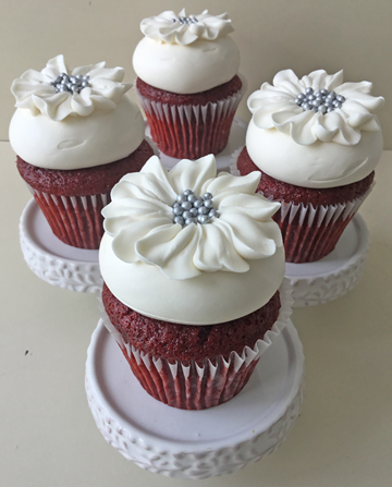 Red velvet cupcakes, filled with cream cheese, topped with vanilla buttercream and decorated with buttercream flowers with silver nonpareils