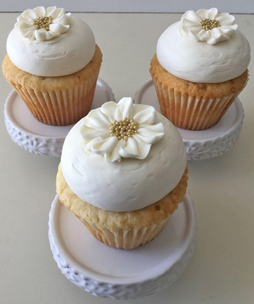 Vanilla cupcakes, topped with vanilla buttercream, decorated with buttercream flowers with gold nonpareil centers