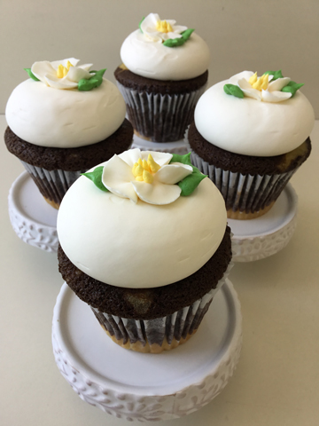 Marble cupcakes, topped with vanilla buttercream and decorated with white blossom flowers with yellow buttercream centers