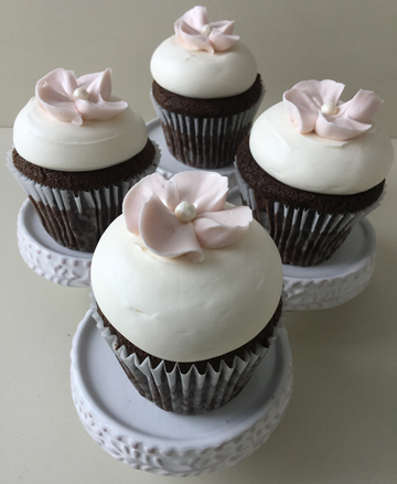 Chocolate cupcakes, topped with vanilla buttercream and decorated with blush buttercream blossom flowers with edible pearl centers