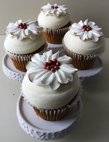 Pumpkin spice cupcakes, topped with cream cheese icing, and decorated with white vanilla buttercream flowers, with rose gold pearl centers and rose gold painted edges